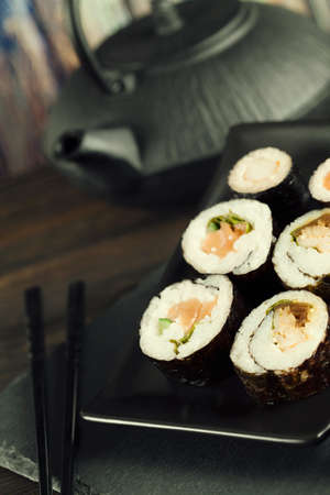 Sushi rolls on black plate and wooden backgroundの写真素材