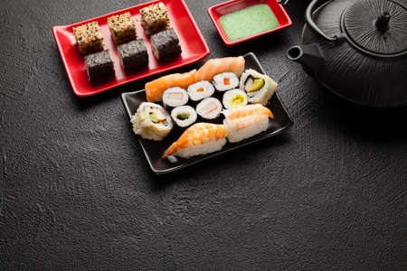 Sushi set and black teapot on black tableの写真素材