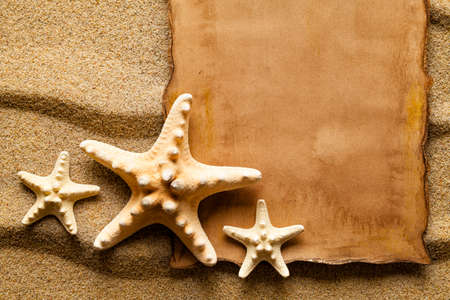 Handmade paper sheet and starfish on sandの写真素材