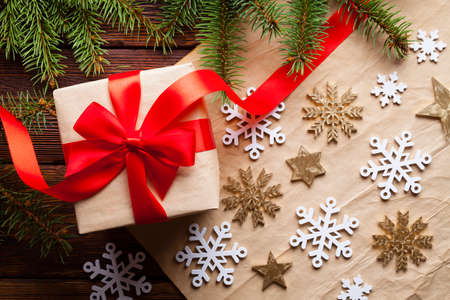 Christmas gift box, spruce tree, snowflakes and stars on paper and wooden backgroundの写真素材