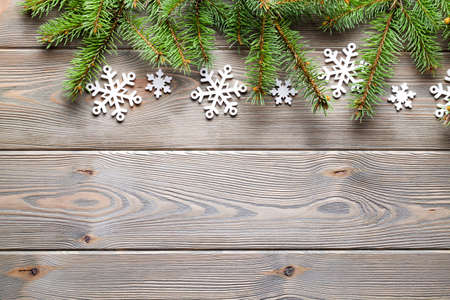 Christmas background - spruce tree and snowflakes on wooden boardの写真素材