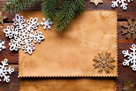 Christmas background - paper sheet, snowflakes, stars and spruce tree on wooden tableの写真素材