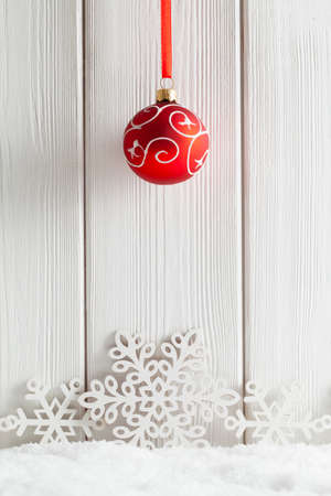 Christmas background - red bauble and snowflakes on snow and white wooden planksの写真素材