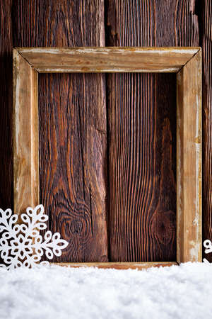 Christmas background - picture frame and snowflakes on snow and wooden wallの写真素材