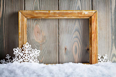 Christmas background - picture frame and snowflakes on snow and wooden wallの写真素材