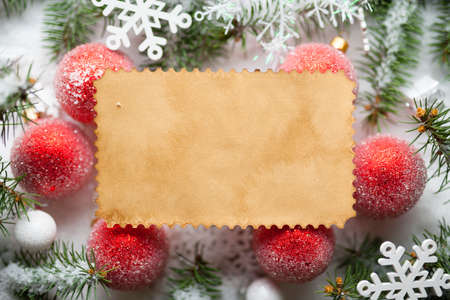 Christmas background - blank paper sheet, baubles, snowflakes and spruce tree on snowの写真素材
