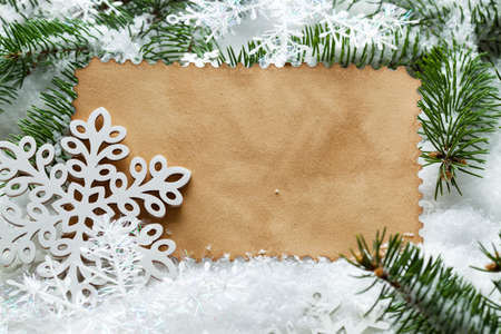 Christmas background - paper sheet, snowflakes and spruce tree on white snowの写真素材