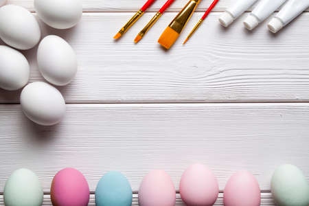 White and colored Easter eggs, brushes and paints on white wooden backgroundの写真素材