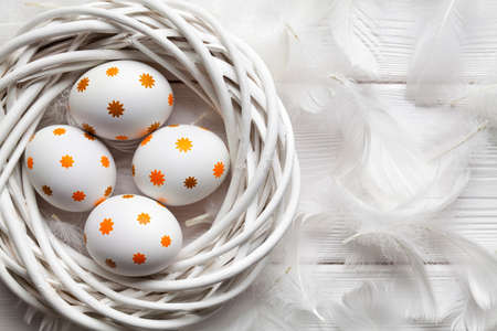 Eastr eggs in the nest and white feathers on wooden tableの写真素材