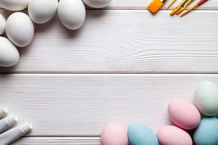 White and colored Easter eggs, brushes and paints on white wooden tableの写真素材