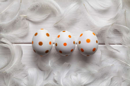 Three Easter eggs and feathers on white wooden backgroundの写真素材