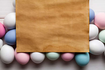 Handmade paper sheet and colorful eggs on white wooden backgroundの写真素材