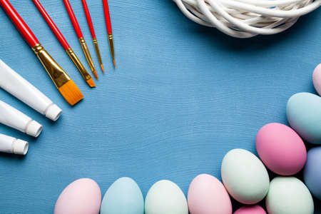 Painted Easter eggs, brushes and paints on blue background as a symbol of painting Easter eggsの写真素材