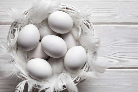 White eggs in basket on white wooden planks backgroundの写真素材