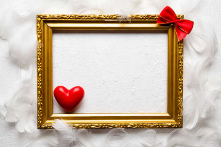 Valentines Day - Gold picture frame, red heart and bow on white backgroundの写真素材