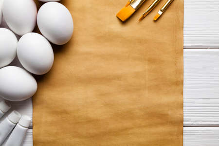 Handmade paper sheet, eggs and brushes on wooden tableの写真素材