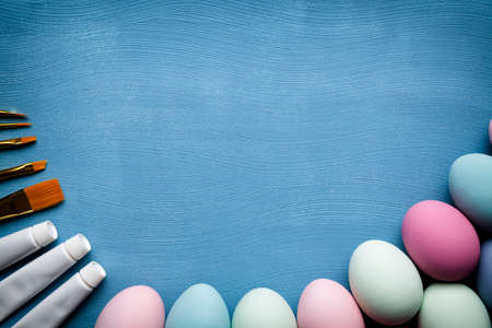Painted Easter eggs, brushes and paints on blue background の写真素材
