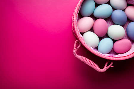 Colored Easter eggs in a basket on pink backgroundの写真素材