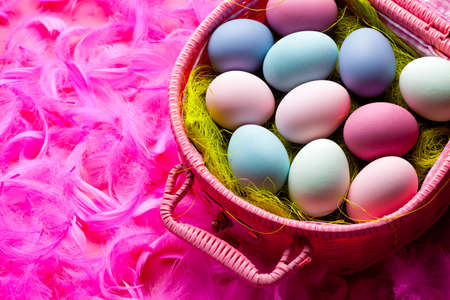 Easter background - colored eggs and feathers on pink background