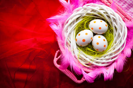 Three white Easter eggs in the nest on red backgroundの写真素材