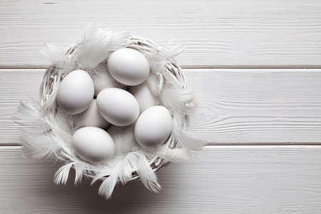 White eggs in basket on white wooden planks backgroundの写真素材