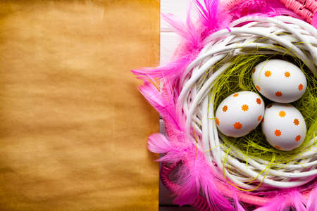 Three painted Easter eggs in the nest and blank handmade paper sheetの写真素材