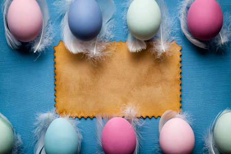 Easter eggs and handmade paper sheet on blue backgroundの写真素材