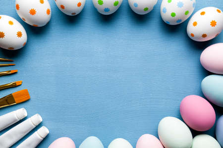 Painted Easter eggs, brushes and paints on blue background の写真素材