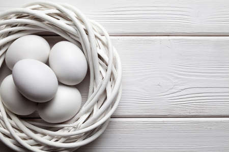 White eggs in the nest on wooden tableの写真素材