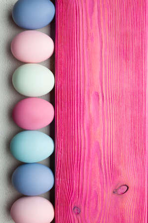 Easter background - colored eggs and pink wooden plankの写真素材