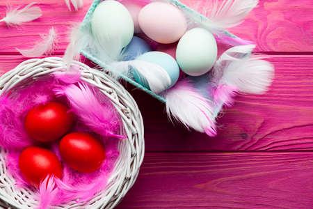 Colored Easter eggs, feathers and baskets on pink wooden backgroundの写真素材
