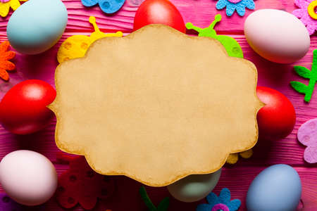 Easter background - blank handmade paper card, eggs and colorful decorations on wooden backgroundの写真素材