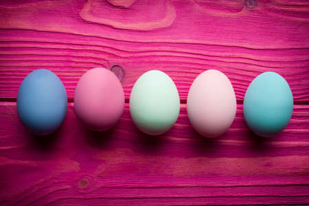 Five painted Easter eggs pink wooden planks backgroundの写真素材