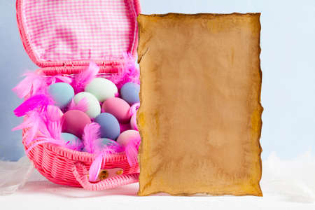 Blank paper sheet and pink basket full of colored eggsの写真素材