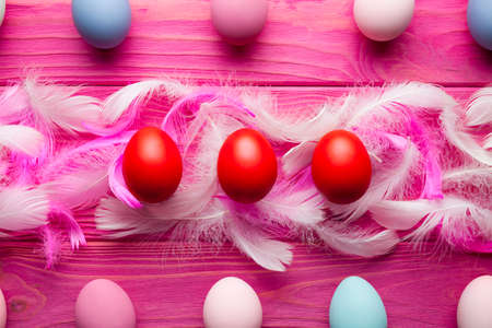Easter background - colored eggs and feathers on pink wooden backgroundの写真素材