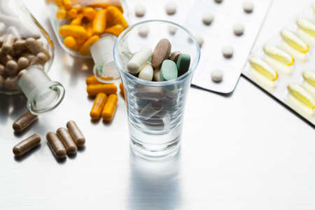 Dose of medicines and various capsules and pills on a steel backgroundの写真素材