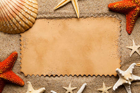 Blank paper card and various shells and starfish on beach sand backgroundの写真素材