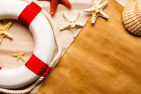 Blank paper sheet, lifebuoy and various starfish on beach sand backgroundの写真素材