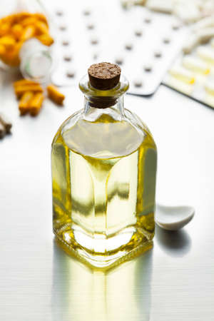 Medicine as a syrup in a glass bottle and various capsules on a metal tableの写真素材