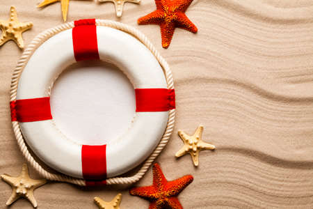 Lifebuoy and various starfish on beach sand backgroundの写真素材