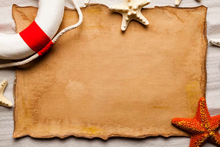 Paper sheet, lifebuoy and starfish on the beachの写真素材