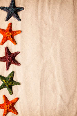Beach background - five colored starfish on beach sandの写真素材