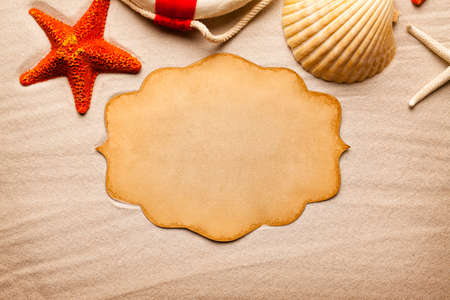 Blank paper card, starfish, shell and lifebuoy on beach sand backgroundの写真素材