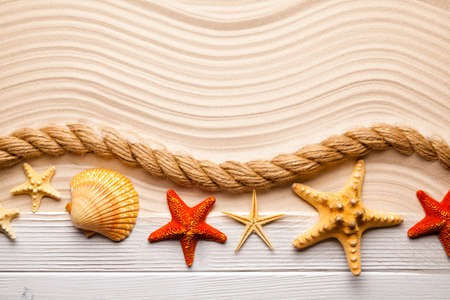 Beach background - starfish, shell, rope and wooden plank on sand background