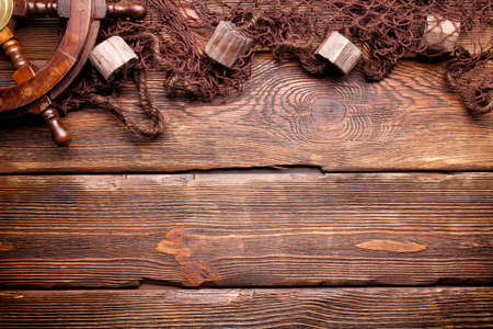 Fishing net and steering wheel on wooden wall backgroundの写真素材