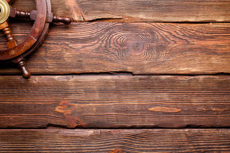 Yachting background - ship's steering wheel on wooden board background