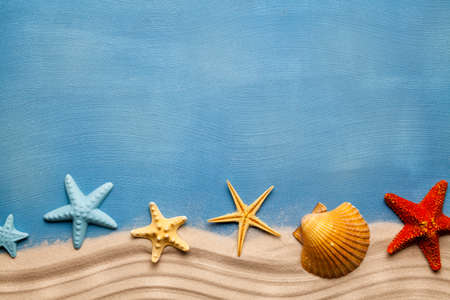 Summertime background - beach sand and seashells on blue tableの写真素材