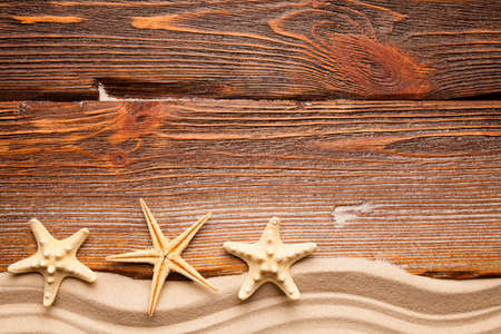 Starfish and beach sand on wooden backgroundの写真素材