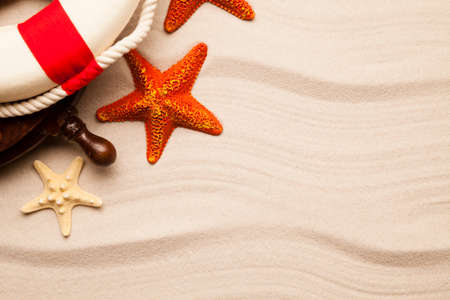 Lifebuoy, steering wheel and starfish on beach sandの写真素材