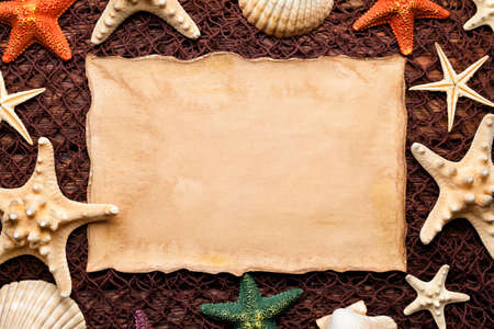 Blank paper sheet and shells on brown fishing net and wooden background